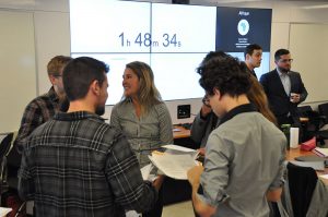 Un groupe d’étudiant.e.s débattent devant un écran géant affichant le compte à rebours.